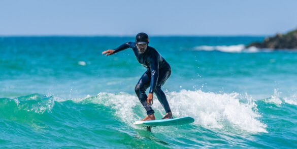 A middle aged man doing some foil surfing or hydrofoil surfing in the sea on a bright sunny day.